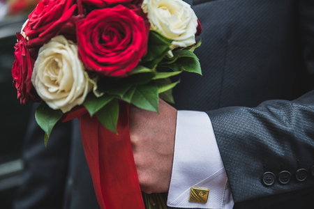 groom holding a bouquet of white daisies, bouquet of white flowers in male handsの写真素材