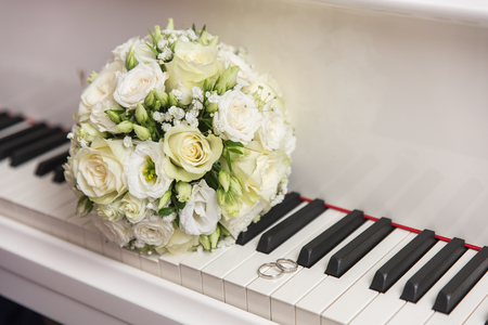 wedding bouquet and ring lying on white piano.の写真素材
