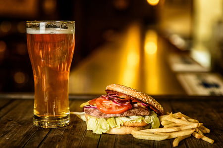Hamburger and light beer at the bar on wooden backgroundの写真素材