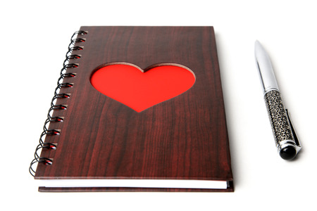 wooden texture notebook with red heart and pen on white backgroundの写真素材