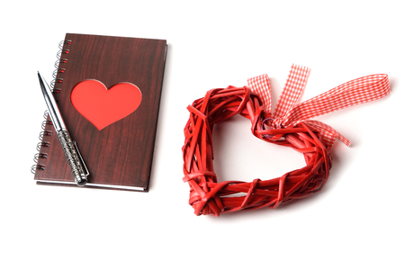 wooden texture notebook with red heart and pen on white backgroundの写真素材