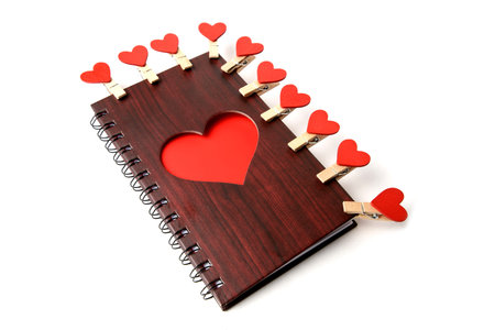 Notepad c wooden texture with red heart and clothespins on a white backgroundの写真素材