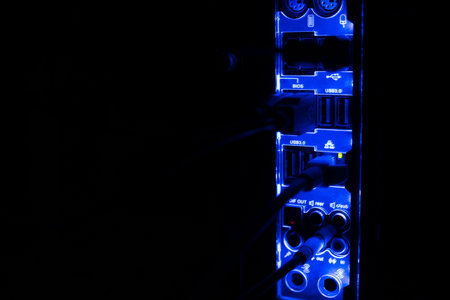 Blackout, blurred borders. Close up of blue network cables connected to black switch glowing in the...