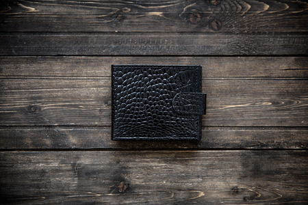 Dark leather wallet on wooden background top viewの写真素材