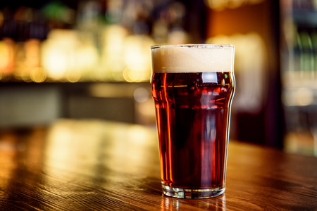 A glass of dark beer on counterの写真素材