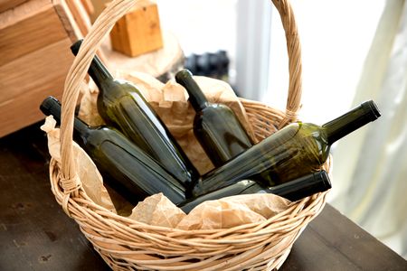 Straw basket with green glass wine bottles in it. の写真素材