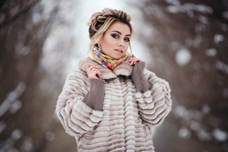 Beautiful girl in fur coat in winter in the forestの写真素材