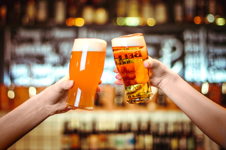 Two friends toasting with glasses of light beer at the pub. Beautiful background of the Oktoberfest. fine grainの写真素材