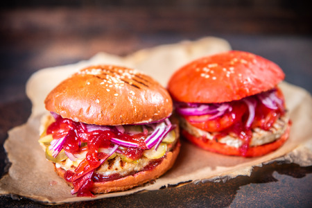 Fresh two homemade burgers on wooden board over dark wooden background.の写真素材