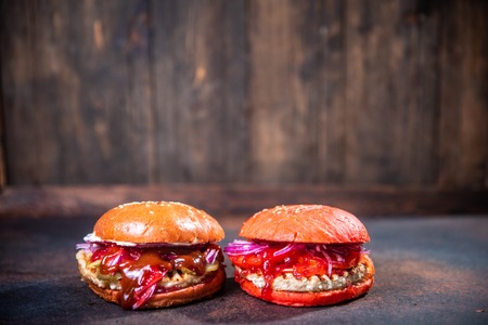 Fresh two homemade burgers on wooden board over dark wooden background.の写真素材