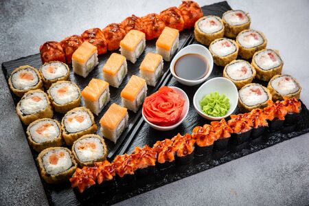 From above composition of sushi, rolls, soy sauce, ginger and wasabi served on black wooden boardの写真素材