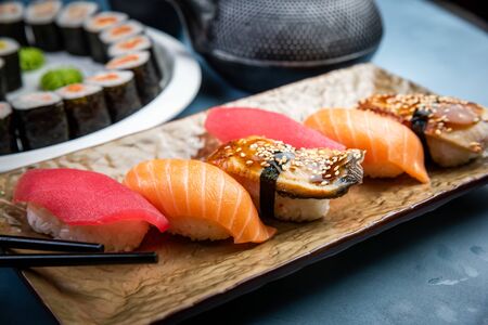 From above composition of sushi, rolls, soy sauce, ginger and wasabi served on black wooden boardの写真素材