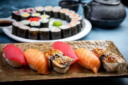 From above composition of sushi, rolls, soy sauce, ginger and wasabi served on black wooden boardの写真素材