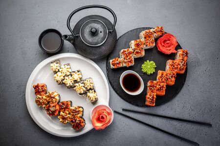 From above composition of sushi, rolls, soy sauce, ginger and wasabi served on black wooden boardの写真素材