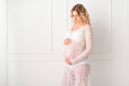 Beautiful Pregant blonde woman holding his belly in light studyの写真素材