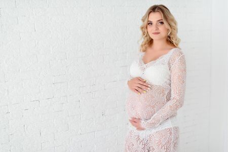 Beautiful Pregant blonde woman holding his belly in light studyの写真素材