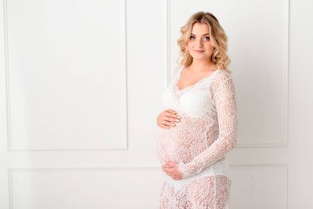 Beautiful Pregant blonde woman holding his belly in light studyの写真素材