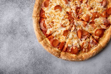 Delicious hot homemade Pepperoni pizza on the wooden table. Pepperoni Pizza - Fresh homemade pizza with pepperoni, cheese and tomato sauce on rustic black stone background with copy space.の写真素材
