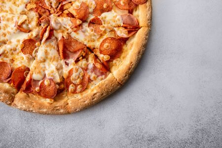 Delicious hot homemade Pepperoni pizza on the wooden table. Pepperoni Pizza - Fresh homemade pizza with pepperoni, cheese and tomato sauce on rustic black stone background with copy space.の写真素材