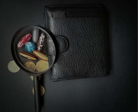 wallet, magnifier, various coins and pebbles on black backgroundの写真素材