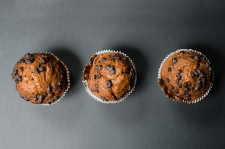 three chocolate muffins on a dark backgroundの写真素材