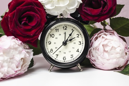 alarm clock with beautiful flowers on table, rosesの写真素材