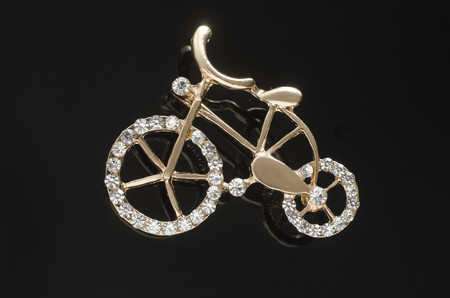 golden brooch bicycle with gems isolated on black backgroundの写真素材