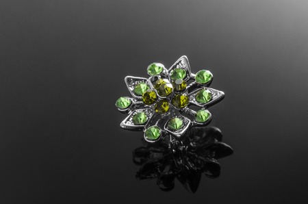 silver brooch with emeralds isolated on blackの写真素材