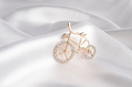 golden brooch bicycle with gems on silkの写真素材