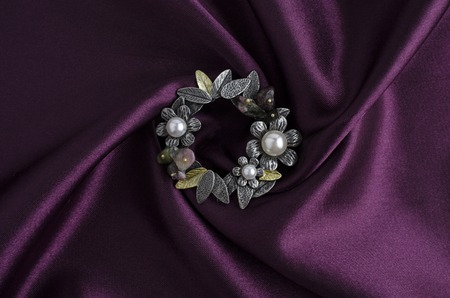 round brooch with flowers and pearls on white silkの写真素材