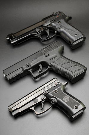 three black pistols on a black background.の写真素材