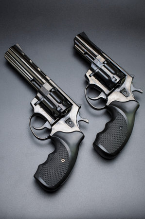 two shiny black revolvers on a black background.
