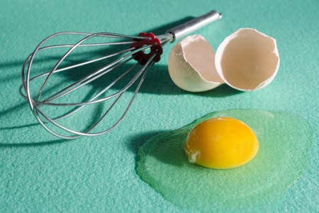 raw broken egg and whisk isolatedの写真素材