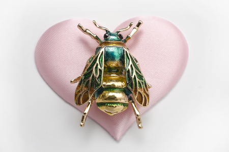 golden brooch bee on a silk heartの写真素材