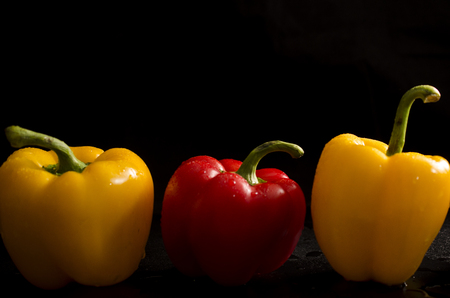 bell peppers yellow and red on black backgroundの写真素材