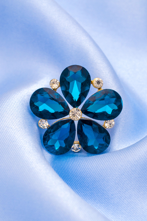 brooch flower with blue stones isolated on silkの写真素材
