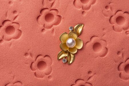 gold brooch flower with a pearl on the pink sandの写真素材