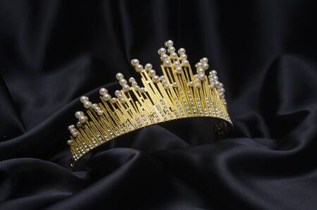 golden crown with pearls and diamonds isolated on black silkの写真素材