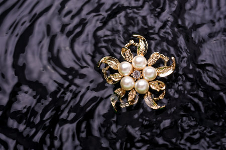 gold brooch flower with a pearl and gems in the waterの写真素材