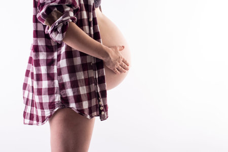 pregnant woman in a man's shirt on a white backgroundの写真素材