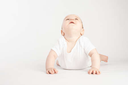 baby stands in her arms and looks up, on a white backgroundの写真素材
