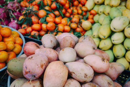 Mangoes and other fruits on the counter in the Asian street marketの写真素材
