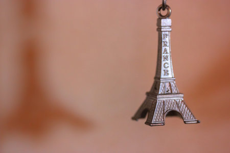 Metal keychain in the form of the Eiffel Tower in Paris, France. Souvenir from the trip close-up on orange backgroundの写真素材