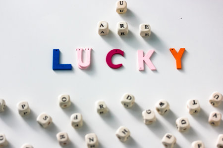 You are lucky colorful words written on wood blocks, white table background and abc alphabet, black and white letters on wooden blocks. Business success and motivation for actionの写真素材