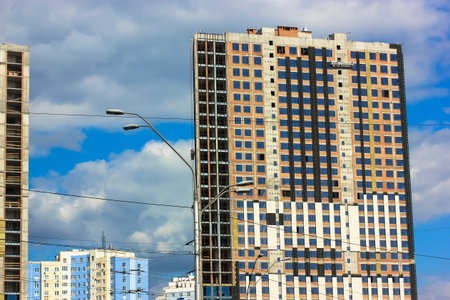 Glass facade of a modern building in a big city: a construction crane against a blue sky.