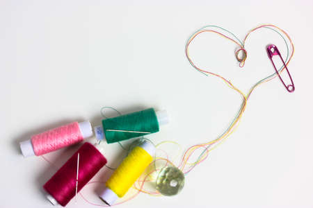 A heart of multicolored thread. Love for sewing and needlework. Threads in the coils on the surface of the white table.の写真素材