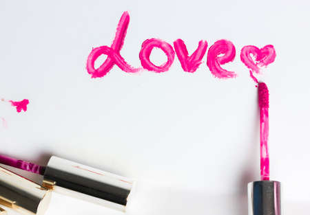 The word love written with pink liquid lip gloss on white paper. A declaration of love on Valentine's Day. Place for the text. High quality photoの写真素材