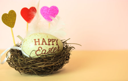 Easter egg with Happy Easter inscribed in a nest, decorative multicolored hearts and a white...