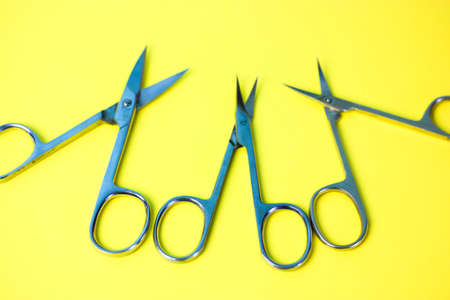 Set of sharp steel manicure scissors isolated on the yellow surface. Professional tools for manicure and pedicure. Open scissors on the table. Beauty Scope. Top view. Flatly.の写真素材