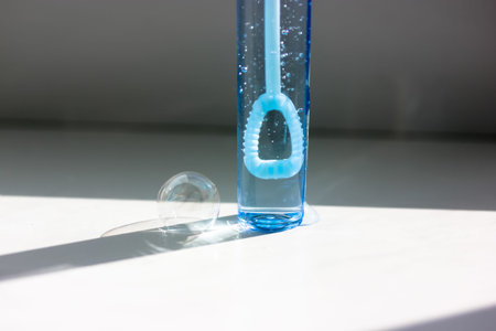 Blue plastic bottle of soap bubbles isolated on white background. Contrast shadows from the soap bubble jar. Soap bubbles flying. Children's fun.の写真素材